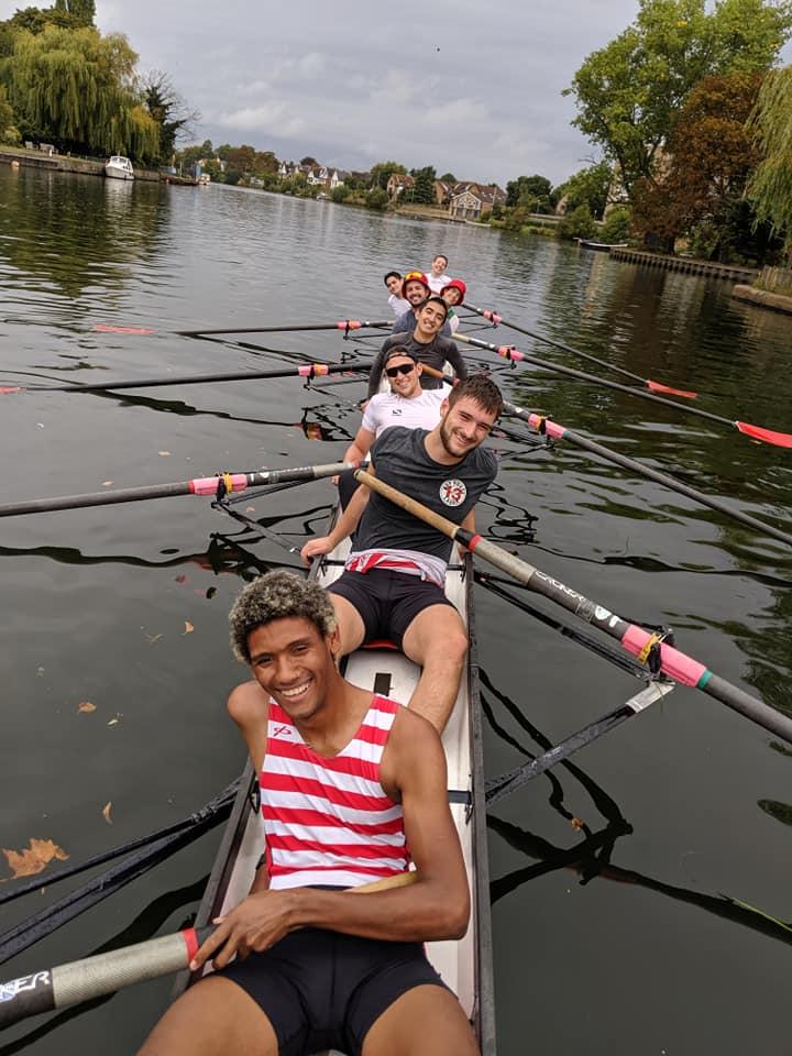 A group of 8 men sat in a rowing boat on the river Thames