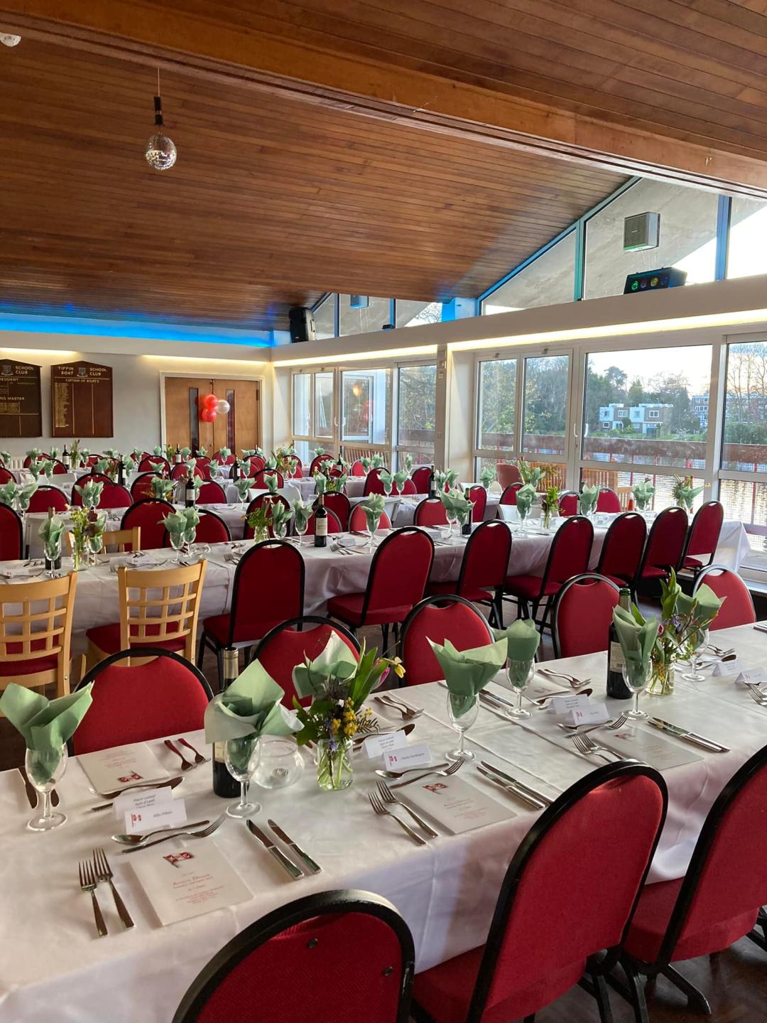 A large event space with long white tables and red chairs set out.