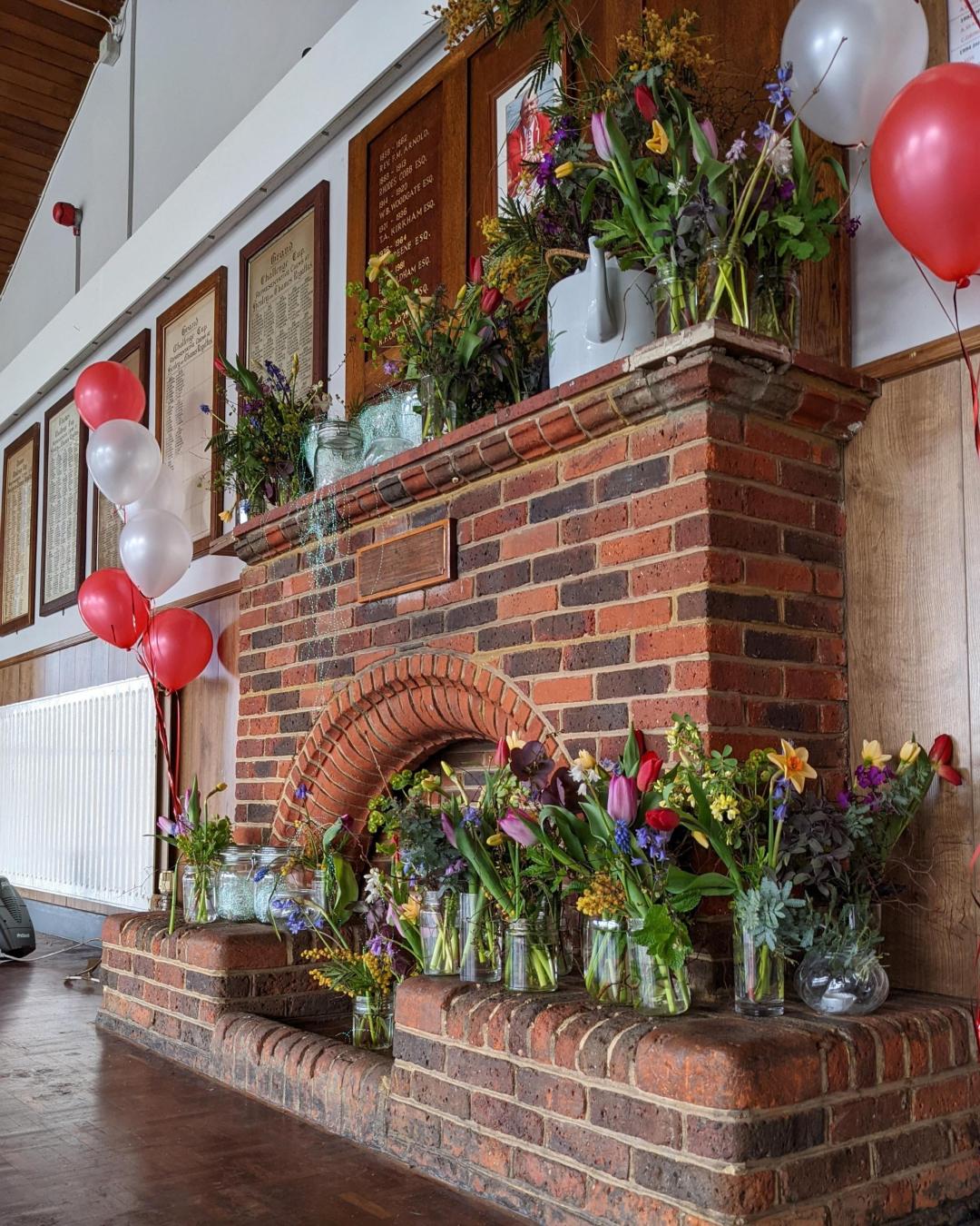 A brick fireplace covered in balloons and flowers