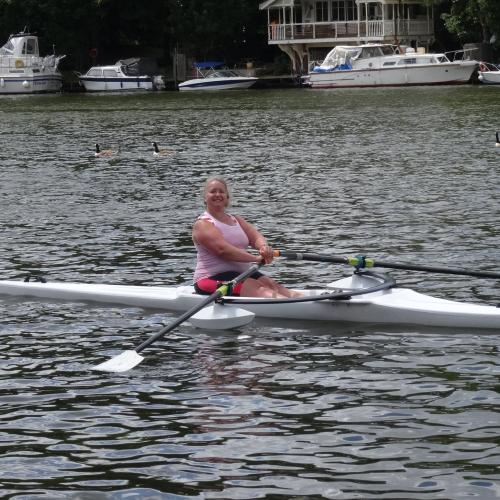 A woman sitting in single rowing boat with stabilisers attached